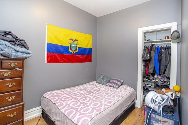 bedroom with baseboards, a closet, and light wood-style floors