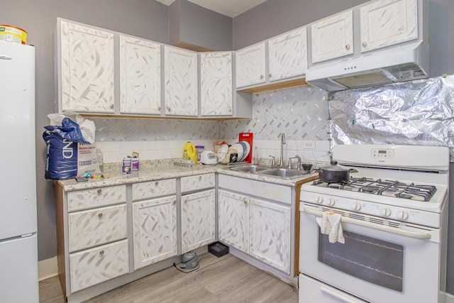 kitchen with white appliances, a sink, light wood-style floors, light countertops, and tasteful backsplash