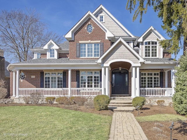 view of front of home with brick siding, a porch, and a front yard