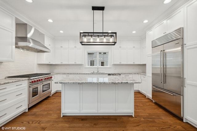 kitchen featuring a kitchen island, high quality appliances, white cabinetry, wall chimney range hood, and dark wood-style floors