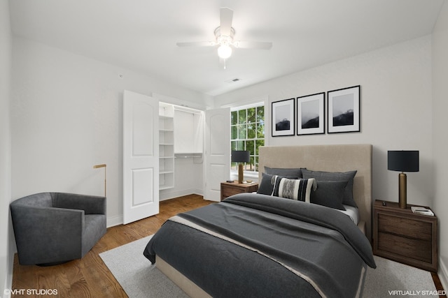 bedroom featuring ceiling fan, wood finished floors, visible vents, baseboards, and a closet