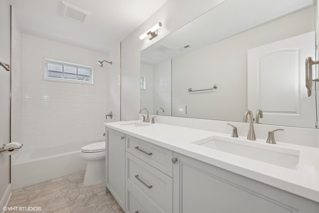 bathroom featuring toilet, double vanity, visible vents, and a sink