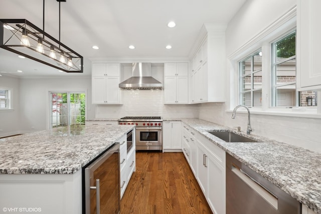 kitchen featuring tasteful backsplash, dark wood-style floors, appliances with stainless steel finishes, wall chimney range hood, and a sink