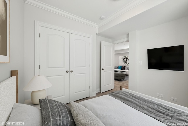 bedroom with a closet, wood finished floors, and crown molding