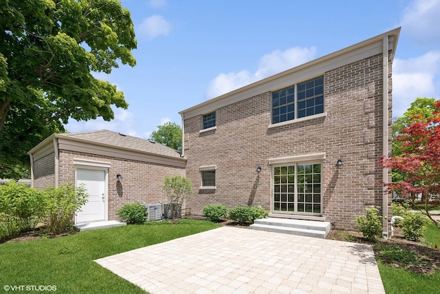 back of house with brick siding, a lawn, entry steps, a patio area, and a garage