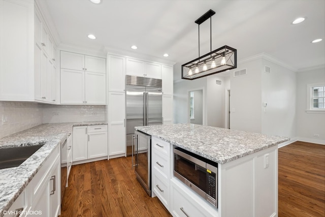 kitchen featuring dark wood finished floors, tasteful backsplash, visible vents, built in appliances, and beverage cooler