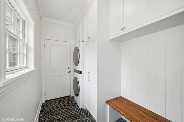 washroom with ornamental molding, stacked washer / dryer, and baseboards