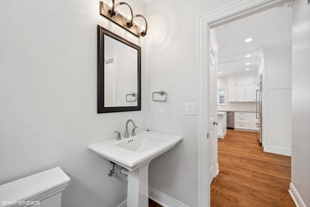 half bathroom with recessed lighting, wood finished floors, toilet, and baseboards