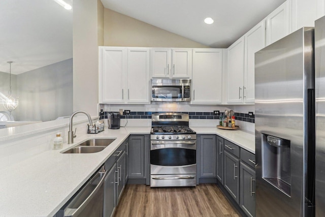 kitchen featuring stainless steel appliances, tasteful backsplash, gray cabinetry, vaulted ceiling, and a sink