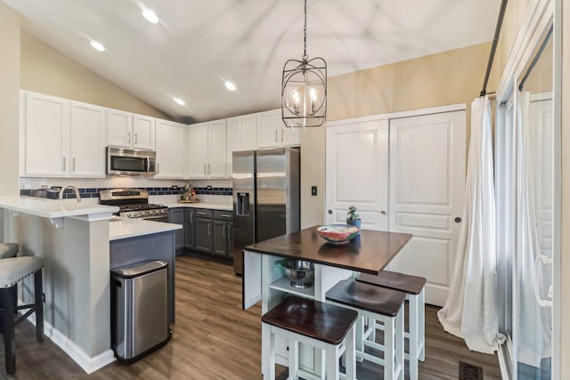 kitchen with a peninsula, visible vents, appliances with stainless steel finishes, backsplash, and a kitchen bar