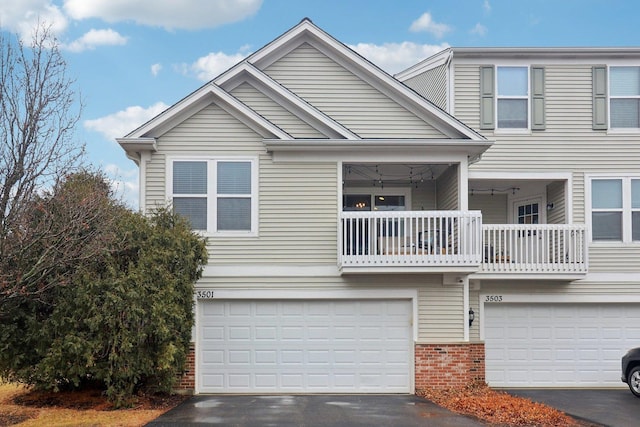 view of front facade featuring a garage, driveway, brick siding, and a balcony