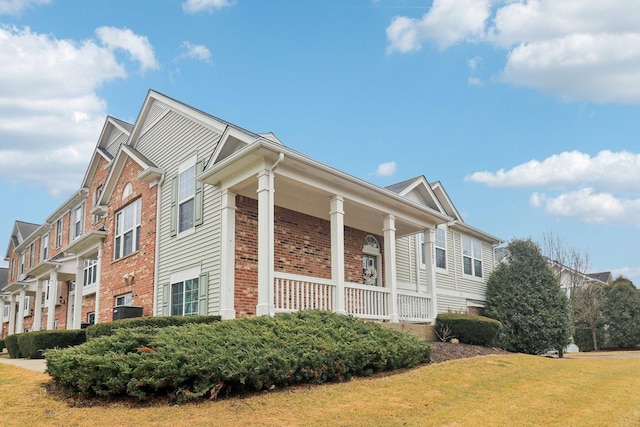 view of property exterior with a porch, brick siding, and a yard