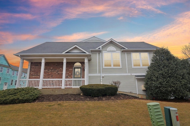 view of front of house featuring a porch, brick siding, and a front lawn