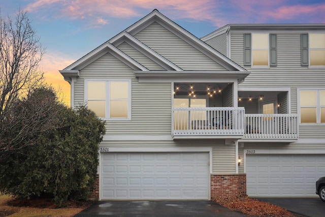 view of front of property with brick siding, driveway, a balcony, and an attached garage