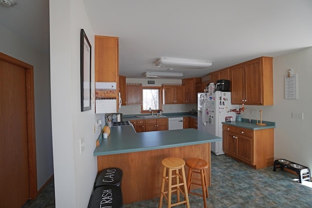 kitchen featuring brown cabinetry, white appliances, a sink, and a peninsula