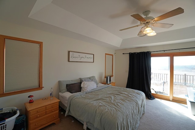 bedroom with carpet, a raised ceiling, a ceiling fan, and access to exterior