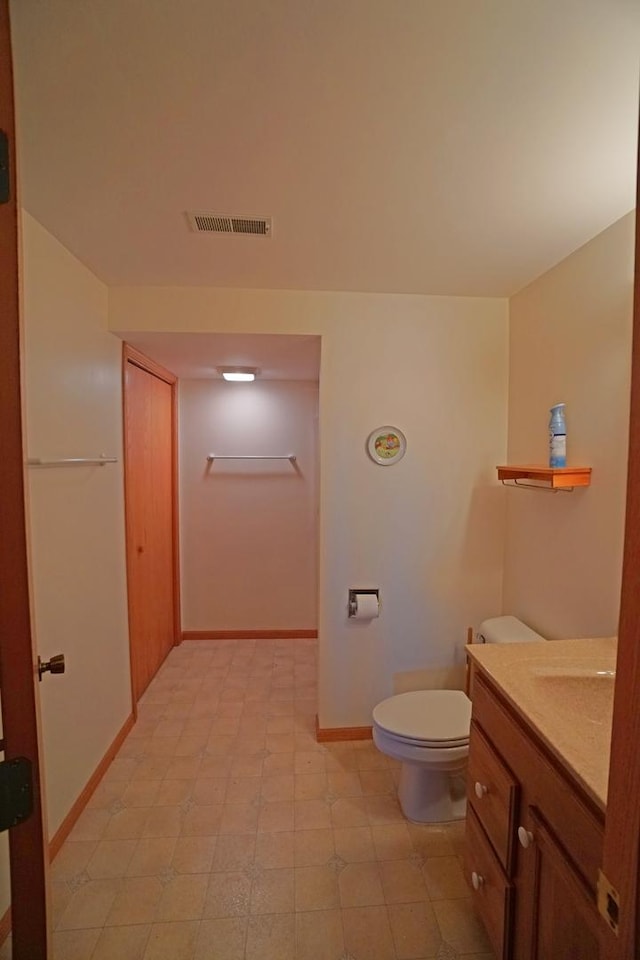 bathroom featuring toilet, vanity, visible vents, baseboards, and tile patterned floors