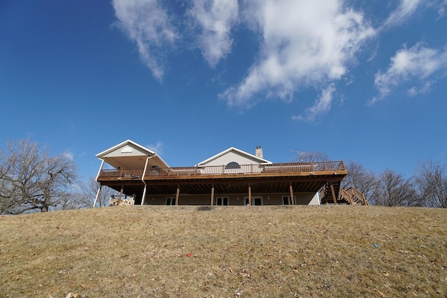 rear view of house featuring stairway, a chimney, and a wooden deck