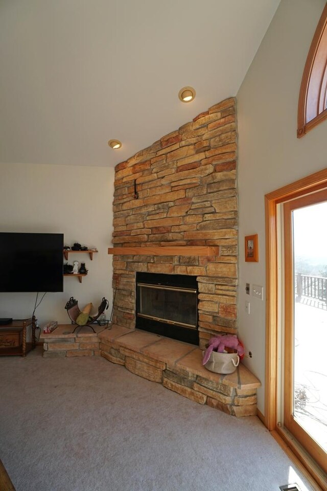 carpeted living area with lofted ceiling, a fireplace, and a healthy amount of sunlight