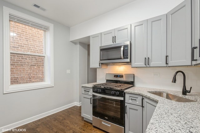 kitchen featuring tasteful backsplash, visible vents, a sink, stainless steel appliances, and dark wood-style flooring