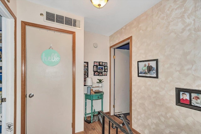 corridor featuring visible vents, wood finished floors, and wallpapered walls