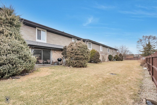 rear view of property featuring a yard and fence