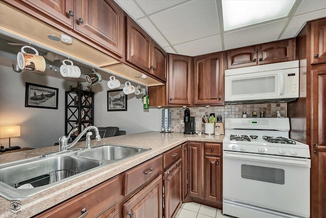 kitchen featuring white appliances, a drop ceiling, a sink, light countertops, and backsplash