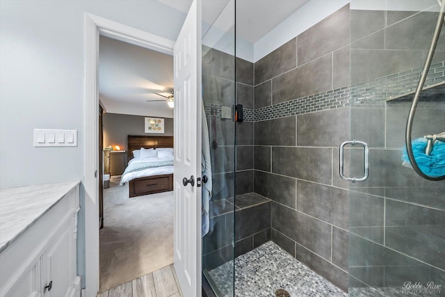 full bath featuring ensuite bathroom, wood finished floors, vanity, a ceiling fan, and a stall shower