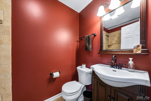 bathroom with baseboards, vanity, toilet, and walk in shower