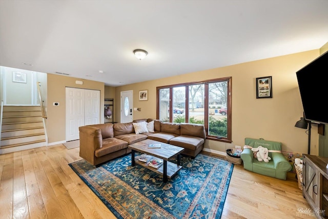 living room with baseboards, visible vents, stairway, and light wood finished floors