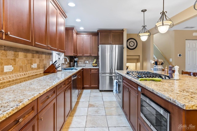 kitchen with appliances with stainless steel finishes, a sink, backsplash, and light stone counters