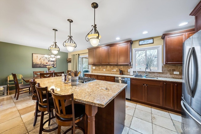 kitchen featuring stainless steel appliances, tasteful backsplash, a sink, and light stone counters