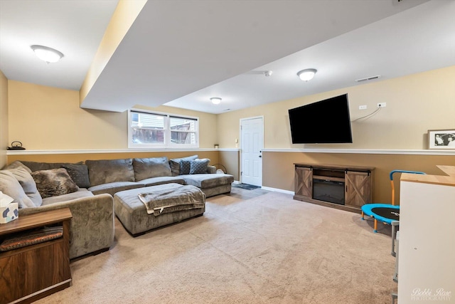 living area featuring carpet, a glass covered fireplace, and visible vents