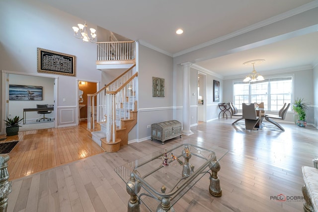 living area with ornamental molding, decorative columns, hardwood / wood-style floors, and an inviting chandelier