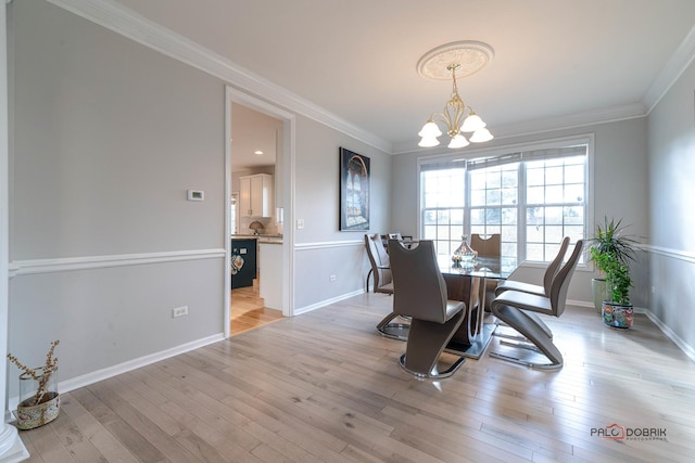 dining room with ornamental molding, light wood-type flooring, and an inviting chandelier