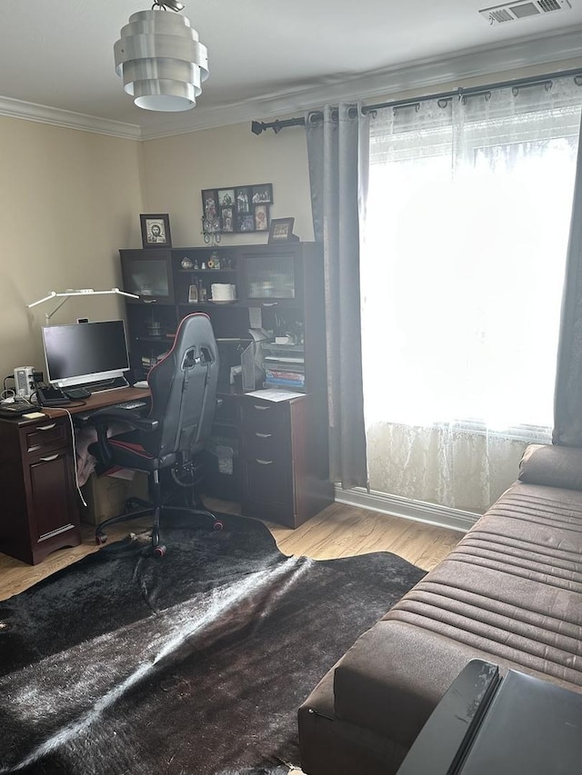 home office featuring visible vents, wood finished floors, a wealth of natural light, and crown molding