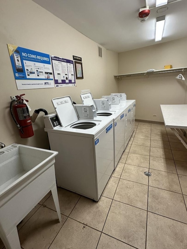 community laundry room with washer and dryer, light tile patterned flooring, a sink, and visible vents