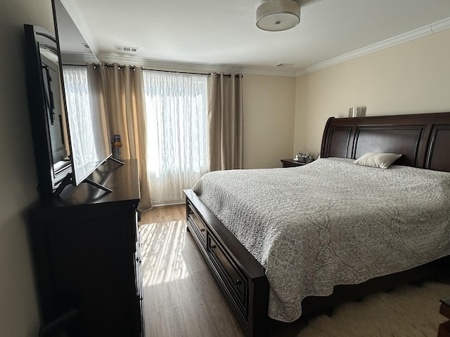 bedroom featuring visible vents, crown molding, and wood finished floors