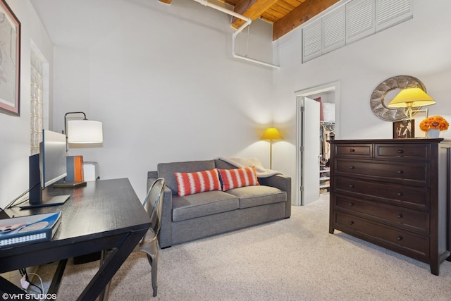 interior space with light carpet, wooden ceiling, a walk in closet, and beam ceiling