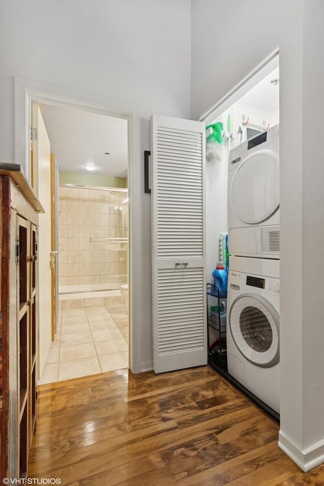 washroom featuring wood finished floors, stacked washer and clothes dryer, and laundry area