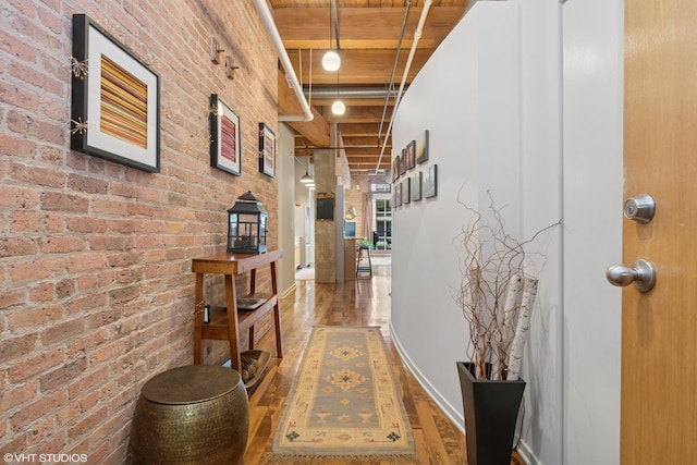 corridor featuring brick wall and wood finished floors