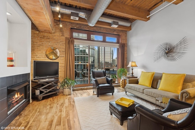 living area with a tile fireplace, wooden ceiling, beamed ceiling, and wood finished floors