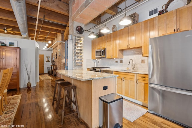 kitchen featuring dark wood finished floors, stainless steel appliances, visible vents, a towering ceiling, and a sink