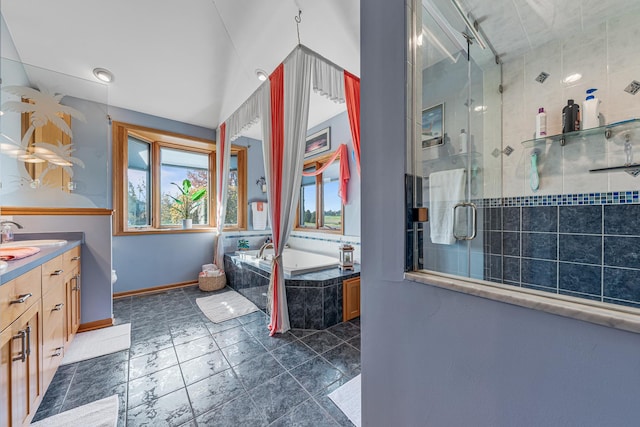 bathroom featuring a stall shower, a garden tub, vanity, and baseboards