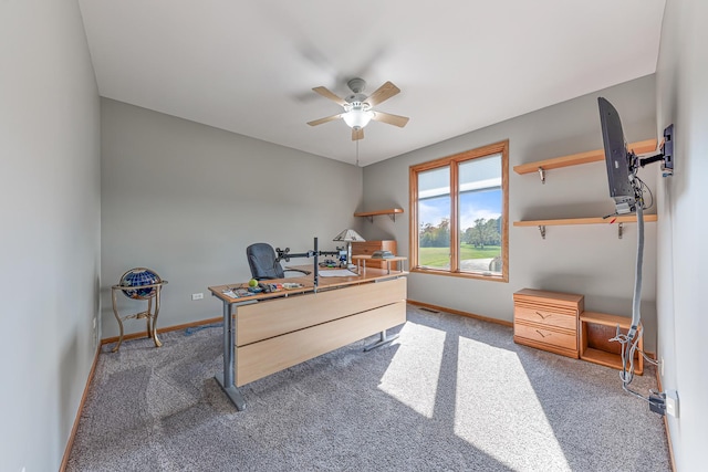 carpeted office space featuring ceiling fan and baseboards