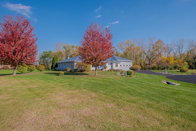 exterior space featuring aphalt driveway and a front yard