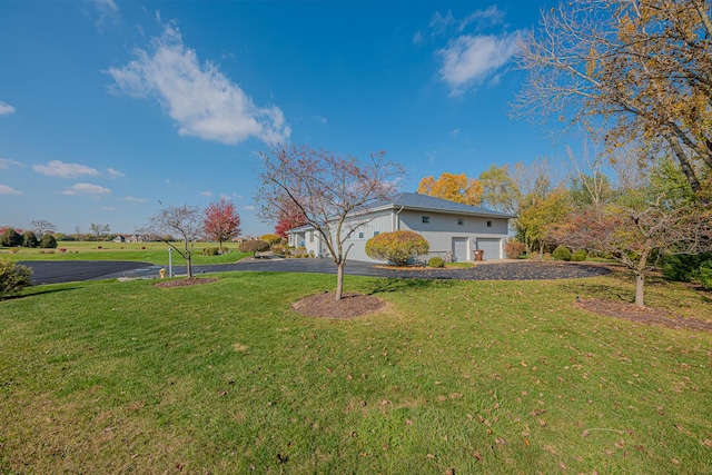 view of yard with a garage and aphalt driveway