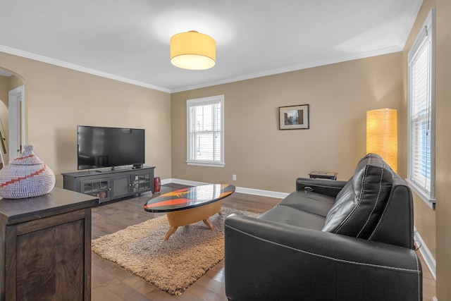 living area featuring arched walkways, crown molding, baseboards, and wood finished floors