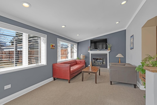 living room with a glass covered fireplace, crown molding, baseboards, and light carpet