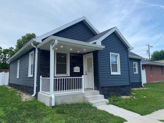 225 W Dakota St, Spring Valley, IL 61362 - bungalow-style home featuring covered porch, stone siding, a front lawn, and roof with shingles